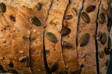 pumpkin seeds, sunflower seeds, sesame seeds, and poppy seeds on sliced loaf of white seeded bread - 532548648