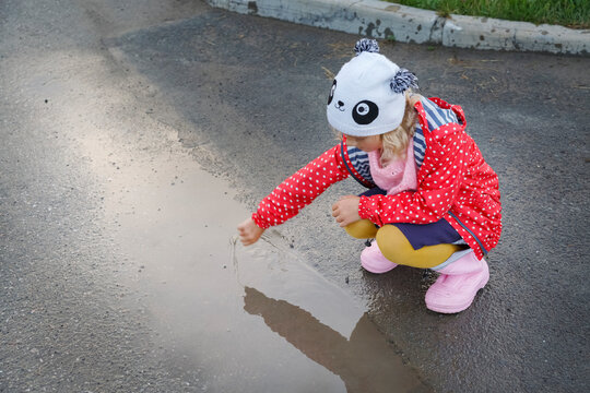 Calm child playing with puddle on countryside road