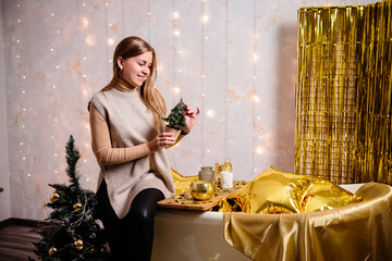 Happy woman in New Year's room. New Year's decoration of the room in golden color. The concept of the holiday and festive design. Home decor for the New Year.