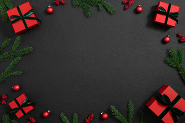 Christmas frame with red gifts, baubles and green fir branches on a black background. Winter holiday. Template, mockup. Copy space, top view, flat lay.