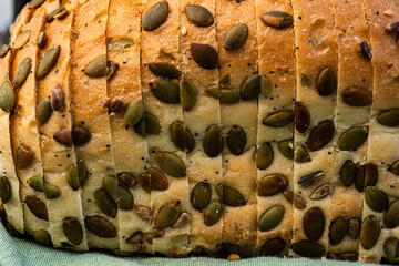 sliced white bread loaf encrusted with pumpkin seeds, sunflower seeds, sesame seeds, poppy seeds - 532550684