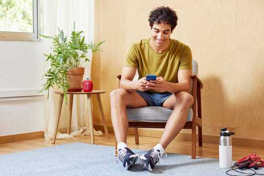 Cheerful sportsman using smartphone at home