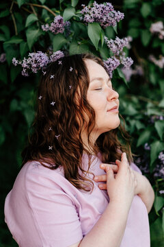 Romantic female with closed eyes standing near lilac tree