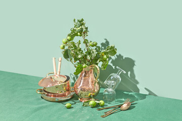 Copper kitchenware decorated with green tree branches.
