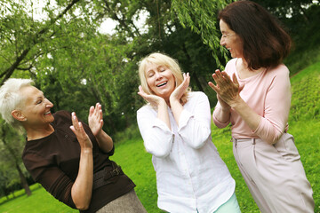 Three female friends in the park celebrate a birthday. Clap your hands, congratulate, rejoice.