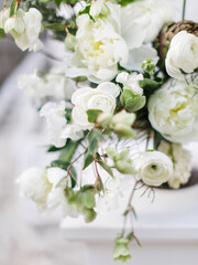 Delicate bouquet in white and green tones. White roses and peonies, green twigs and leaves on a white background.
