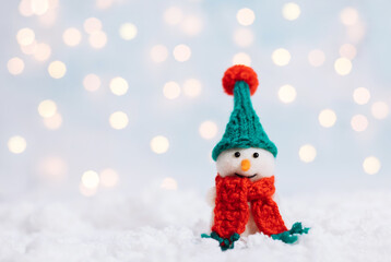 Christmas background with a snowman in a green hat and a red scarf. Greeting card with a happy toy snowman. Happy New Year. Space for text.