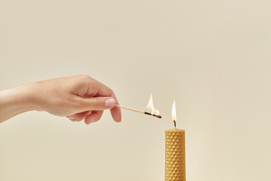 Yellow beeswax candle lit by hand.