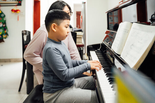 Mother and son playing piano at home
