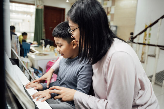 Mother and son playing piano at home
