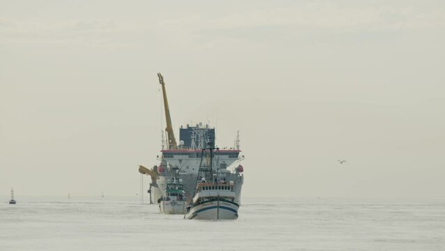 Sand dredger and fishing boat returning from the sea