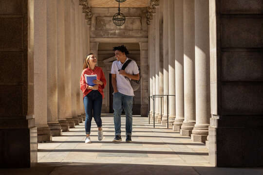 Two happy  Friends University Students walking on outdoor campus
