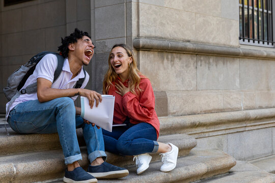 Two Friends laugh with fun times together on campus 