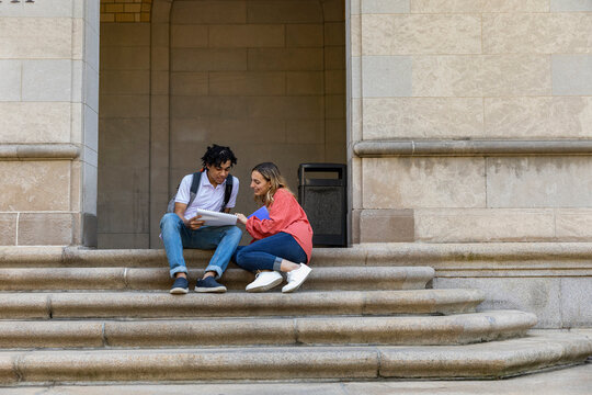 Two cute Friends University Students sit on stone steps 