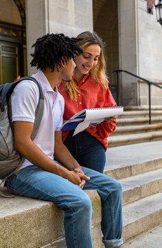 Two cute Friends University Students review assignment in hallway 