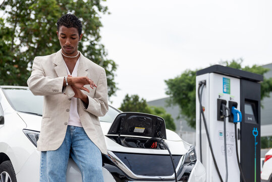 Black man waiting  While Recharging Electric Vehicle