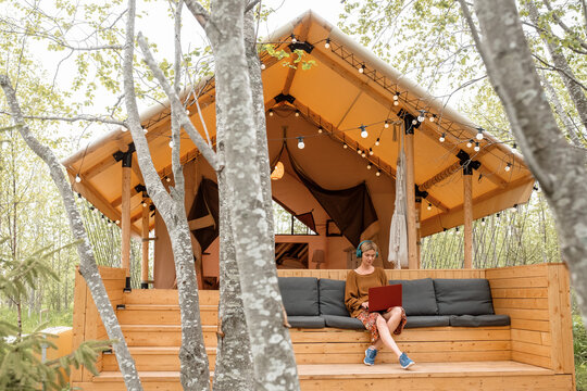Female freelancer using laptop outside summerhouse