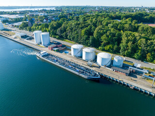 Aerial view of oil tankers moored at an oil storage silo terminal. Aerial view of oil tankers and...