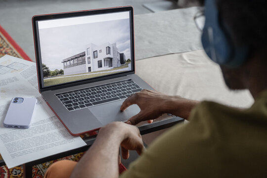 Male architect browsing building plans on laptop