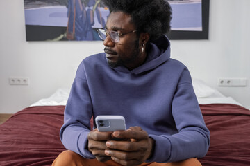 Black male with mobile phone looking away
