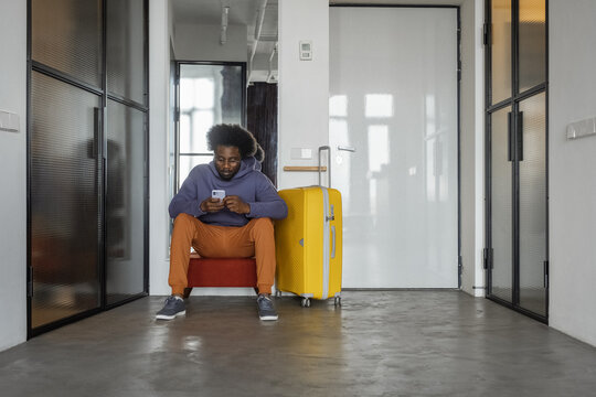 Black traveler using smartphone in corridor