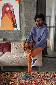 Calm black man sitting on armrest of couch