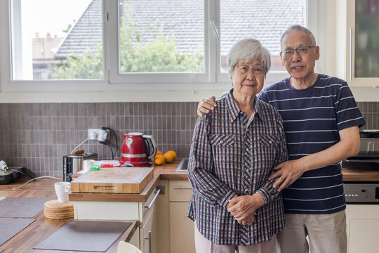 mature senior asian couple portrait looking at camera at home kitchen 