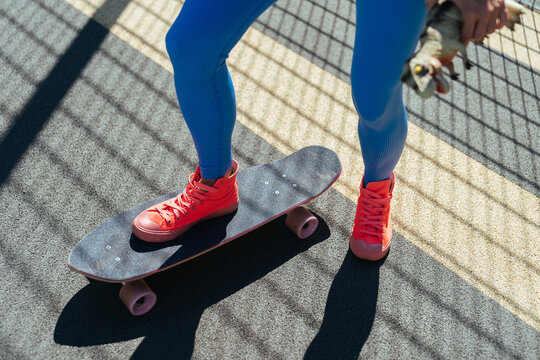 A girl in bright sportswear rides a skateboard.