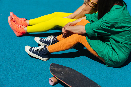 Girls in bright sportswear relax on a sports field.