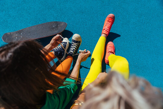 A girl ties her shoelaces on sneakers.