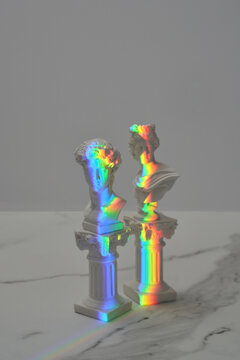 Antique statues with abstract rainbow prism reflection.