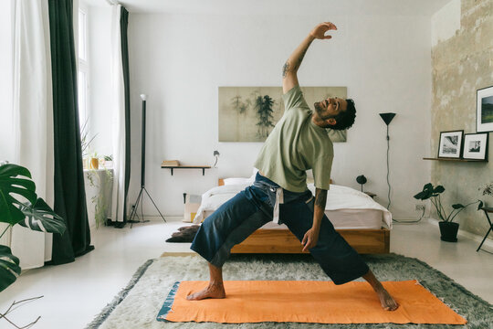 Young Man Doing Yoga in Bright White Bedroom