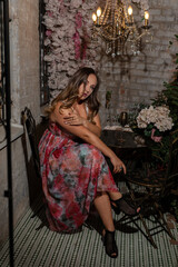 a girl in a pink evening puffy dress with a hairstyle and makeup in a hotel on a balcony in a luxury apartment