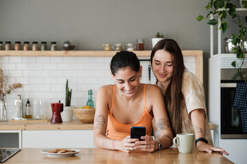 Couple using mobile phone in the kitchen