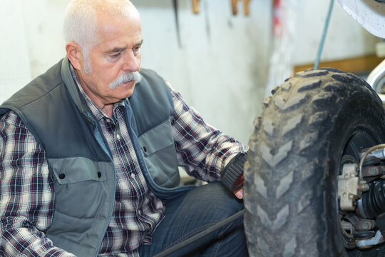senior man changing tyre in his workshop