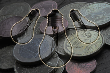 illustration on the theme of the cost of electrical energy, with euro coins in the background and light bulbs in transparency