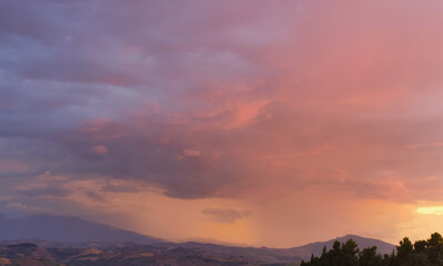 Nebbie e nuvole rosse al tramonto sopra le montagne