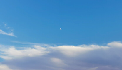Luna bianca calante nel cielo azzurro sopra le nuvole