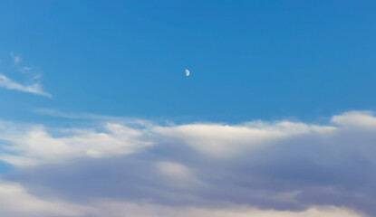 Luna bianca calante nel cielo azzurro sopra le nuvole