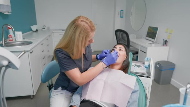 Professional Woman Dentist Examines a Female Patient and Prescribes Treatment in a Modern Dental Clinic. Oral Hygiene. Concept of Healthcare and Medicine. Slow Motion. 