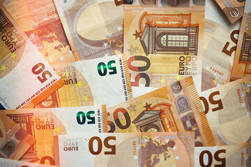 50 Euro money currency banknotes background with lighting. European paper money backdrop with 50 euros bills. Financial investment, savings, income earnings concept.