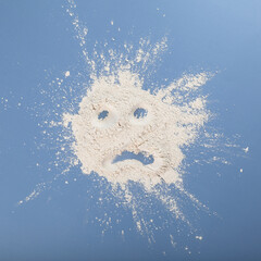 Titanium dioxide, TiO2. Pile of white chemical powder on blue surface with painted sad smile....