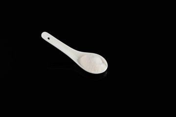 Carrageenan Gum Powder in ceramic spoon on dark background. Food additive E407 or E407a. Refined...