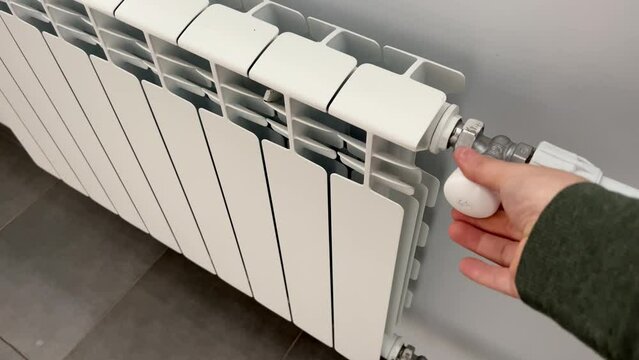 Modern bimetallic radiators for space heating. A person turns on the faucet on the battery panel to pump water and heat the room. Heating the room with batteries in the cold season. The crisis 