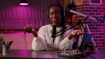 African american woman vlogger talking to audience while recording podcast using audio mixer and...