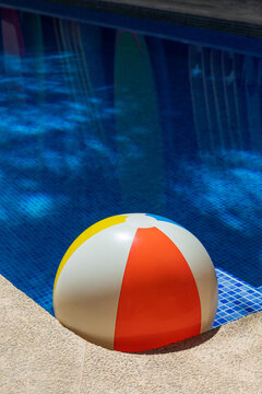 Beach ball in a swimming pool with water reflections