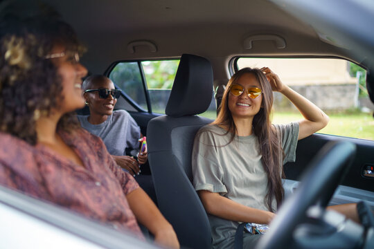 Asian woman with long hair sitting in car with two friends