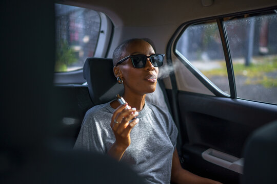 Black woman is blowing smoke after using vape in car