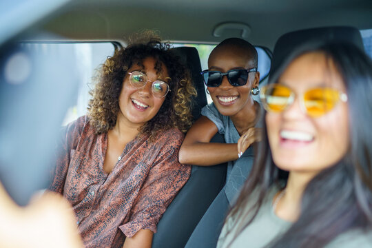 Three women with glasses on smiling for selfie photo in car