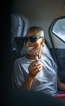 Happy black woman sitting in car holding vape pen
